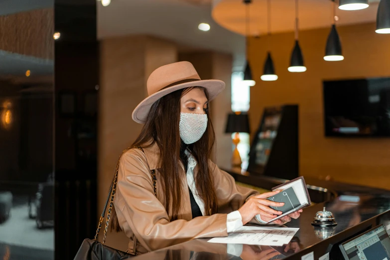 a woman sitting at a counter wearing a face mask, trending on pexels, hotel room, caracter with brown hat, worksafe. instagram photo, thumbnail