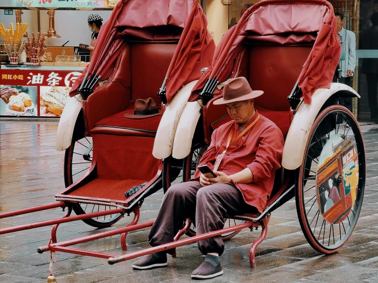 a man sitting in a red and white rickshaw, a colorized photo, pexels contest winner, hyperrealism, tang dynasty, square, maroon, wearing a travel hat