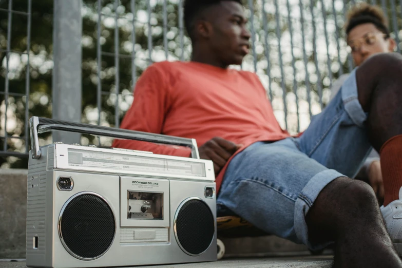 a couple of men sitting next to each other, an album cover, trending on pexels, big ghetto blaster, cinematic shot ar 9:16 -n 6 -g, laying down, calmly conversing 8k