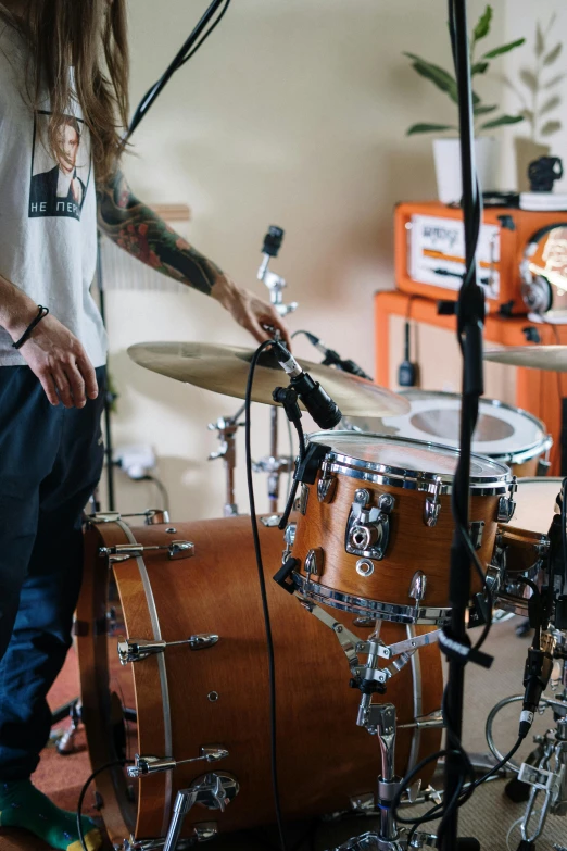 a man sitting in front of a drum kit, trending on pexels, in a workshop, organic detail, aura jared and wires, studio orange