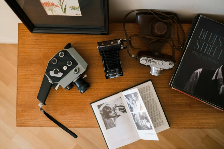 a wooden table topped with a camera and a book, a picture, vhs artefacts, medium format, cinematográfica, brown