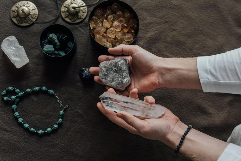 a person holding a crystal in their hands, an album cover, trending on pexels, clay amulets, ((rocks)), various items, alchemical equipment