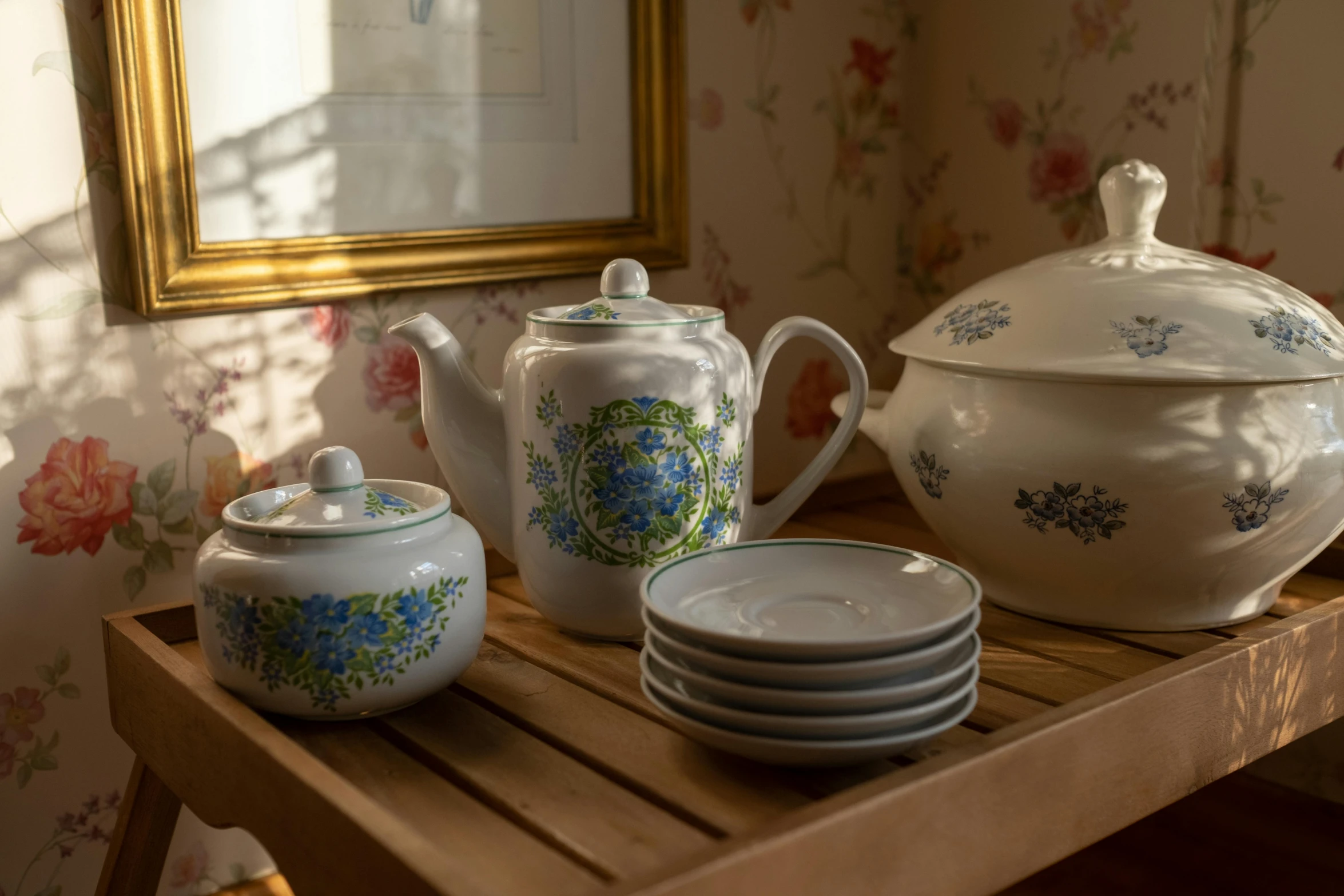 a wooden table topped with plates and bowls, a still life, inspired by Richmond Barthé, rococo, teapot, tones of blue and green, official product photo, cottagecore