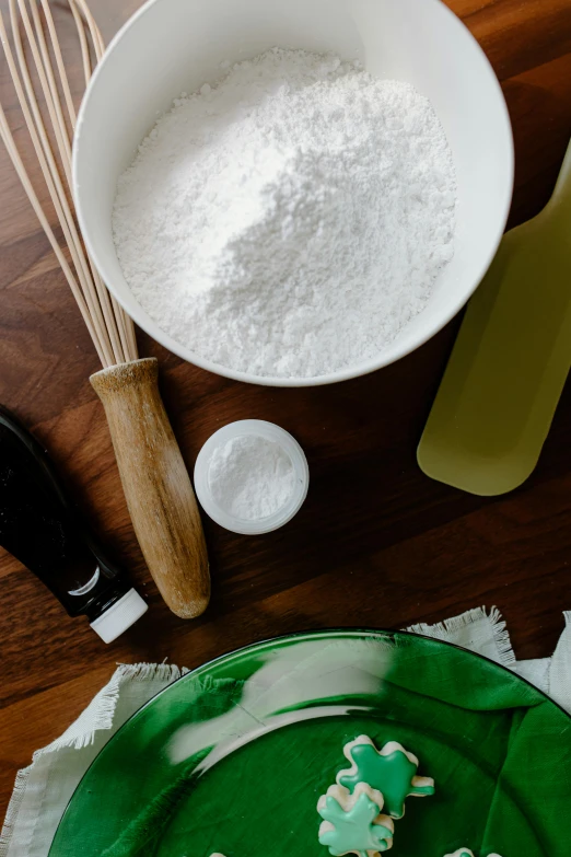 a green plate topped with cookies on top of a wooden table, a still life, by Ben Zoeller, process art, covered in white flour, cooking pizza, tools, skincare