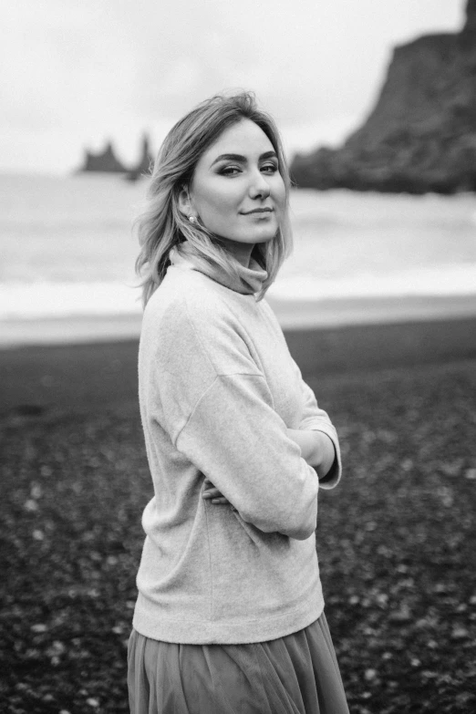 a woman standing on a beach next to the ocean, a black and white photo, inspired by Louisa Matthíasdóttir, pexels contest winner, realism, wearing turtleneck, portrait of kate winslet, in volcano, casual pose