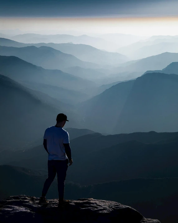 a man standing on top of a mountain overlooking a valley, by Jesper Knudsen, pexels contest winner, lgbtq, snapchat photo, sad men, back - lit