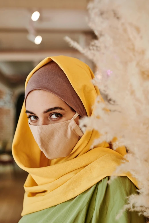 a woman in a hijab talking on a cell phone, trending on pexels, hurufiyya, wearing wheat yellow gauze, ornate mask and fabrics, 64x64, colors: yellow