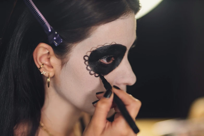 a woman is getting her make up done, inspired by Taro Yamamoto, trending on pexels, lowbrow, la catrina, black eyeliner, rectangular, item