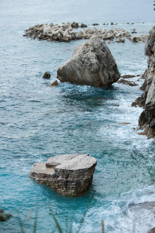 a couple of rocks sitting on top of a body of water, inspired by Nassos Daphnis, romanticism, dubrovnik, grotto, rippling muscles, cliff