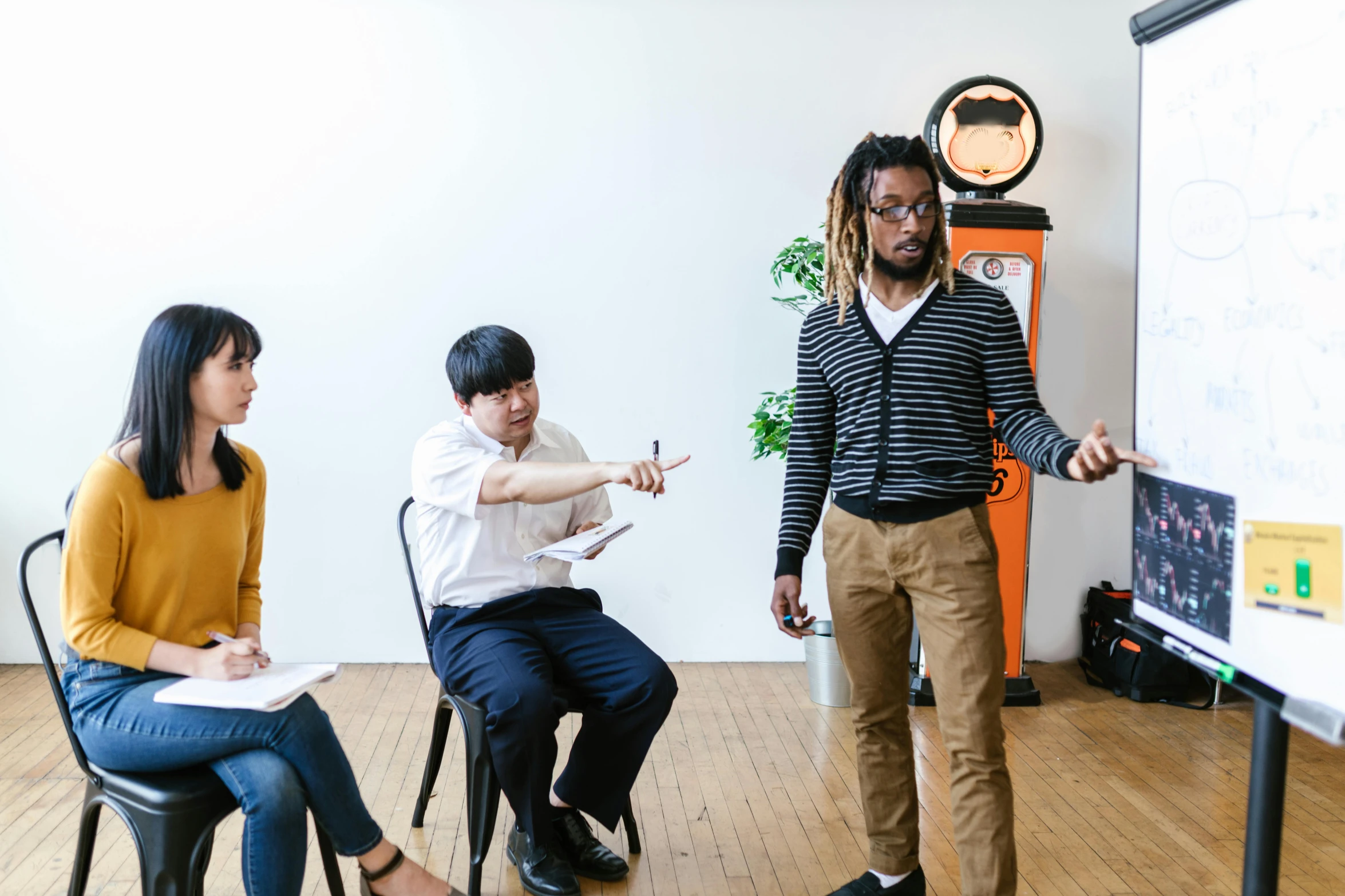 a group of people sitting around a white board, a portrait, by Nina Hamnett, unsplash, art & language, joongwon charles jeong, 3 actors on stage, standing in class, with two characters