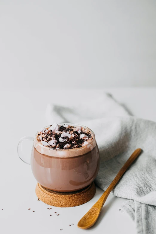 a cup of hot chocolate sitting on top of a table, on a pale background, lulu chen, thumbnail, studio lit