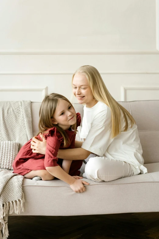 a woman sitting on top of a couch next to a little girl, with long blond hair, friends, full product shot, soft skin