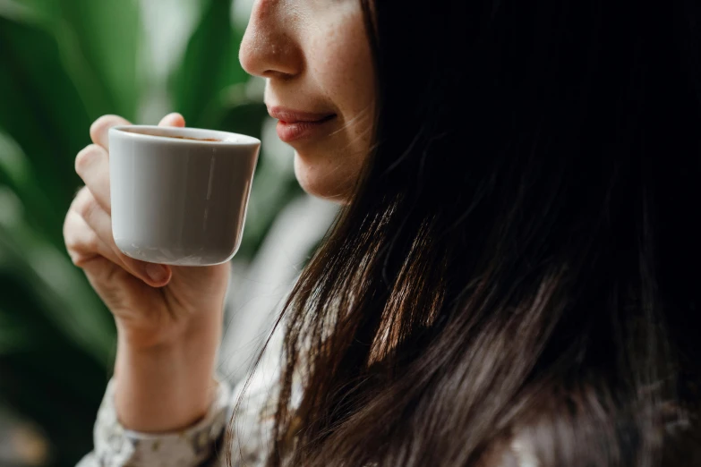 a close up of a person holding a cup of coffee, profile image, girl with dark brown hair, manuka, thoughtful