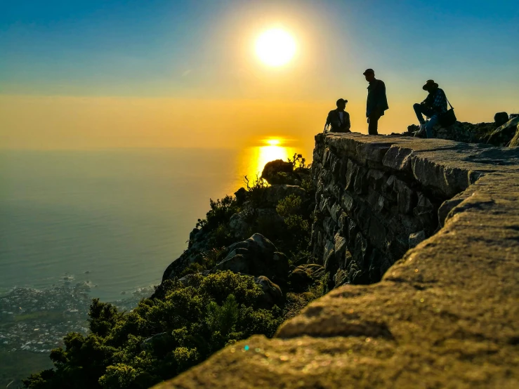 a couple of people standing on top of a cliff, by Niko Henrichon, pexels contest winner, low sun, cape, afternoon hangout, mount