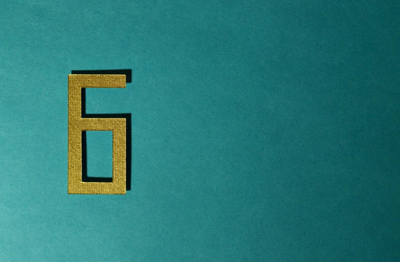 a close up of a letter e on a blue surface, an album cover, trending on unsplash, de stijl, gold and teal color scheme, g6, countdown, n - 6