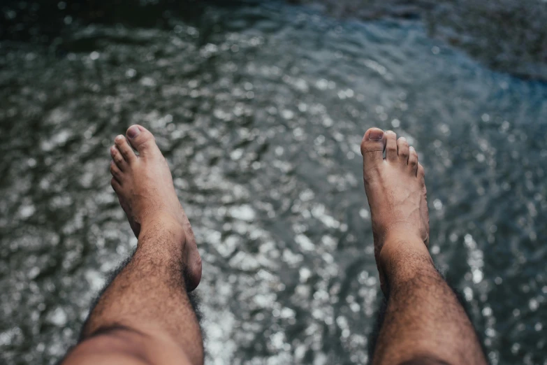 a close up of a person's feet near a body of water, hairy bodies, manly, floating, high above the ground