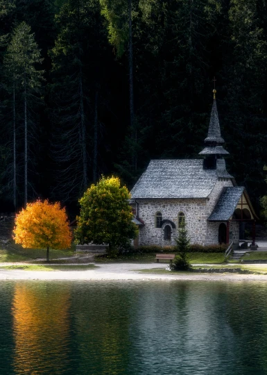 a small church sitting in the middle of a lake, photography of enchanted forest, in the dolomites, fan favorite, black forest