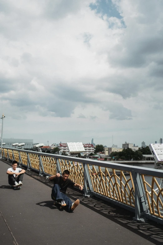 a group of people riding skateboards across a bridge, by Yosa Buson, happening, bangkok, panorama view of the sky, sitting down casually, sad motif