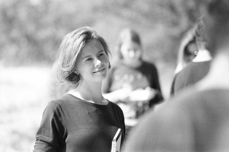 a black and white photo of a woman holding a frisbee, happening, looking across the shoulder, erin hunter, on set, !subtle smiling!