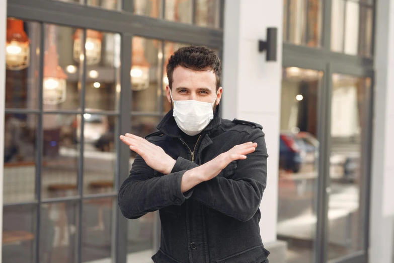 a man wearing a face mask standing in front of a building, pexels, holding his hands up to his face, square, quack medicine, a person standing in front of a