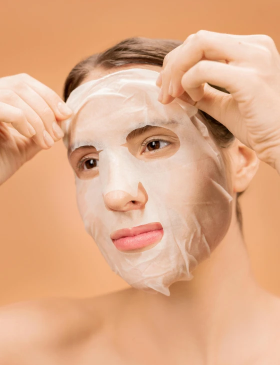 a woman putting a facial mask on her face, an album cover, shutterstock, coerent face and body, transparent, delightful, silicone skin