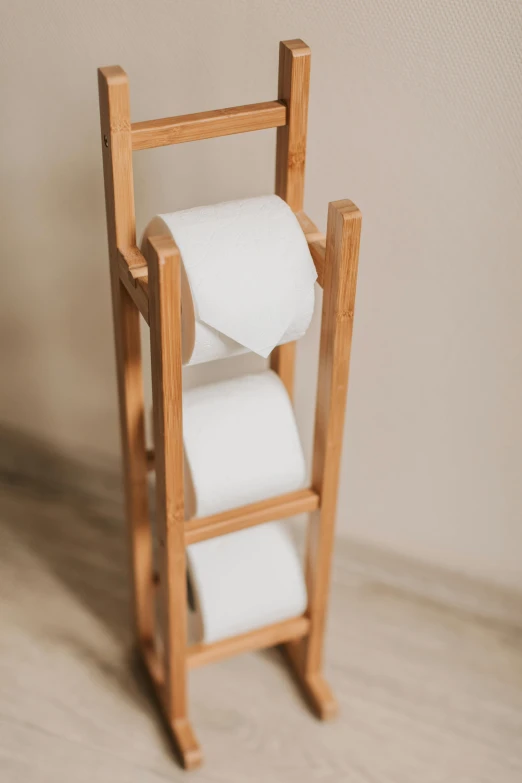 a wooden rack holding three rolls of toilet paper, a picture, unsplash, mingei, detailed product image, portrait of tall, white, eats bambus