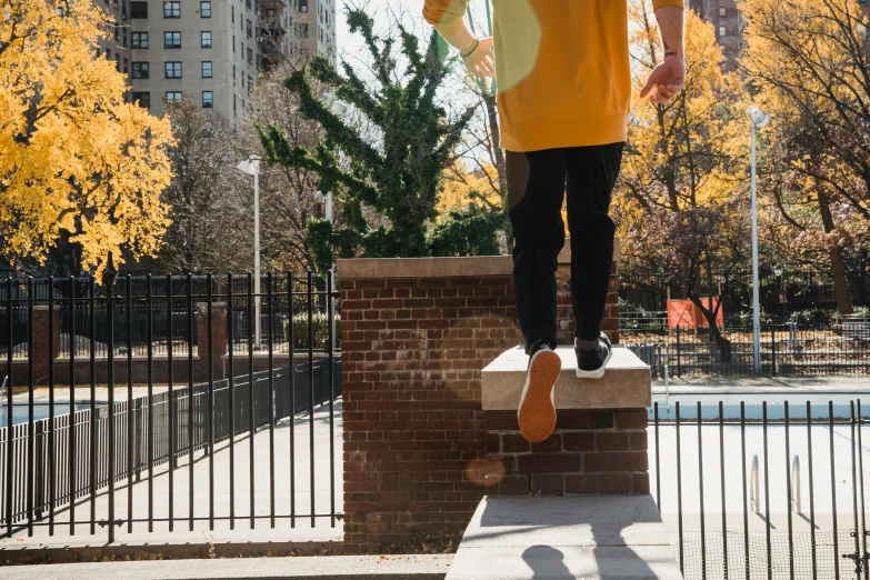 a man flying through the air while riding a skateboard, by Andrew Stevovich, unsplash, realism, long orange sweatshirt, humans of new york, standing astride a gate, sneaker photo