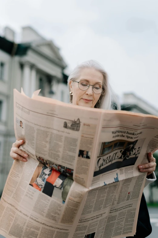 a woman reading a newspaper on a city street, a cartoon, pexels contest winner, long grey hair, gif, attractive photo, librarian
