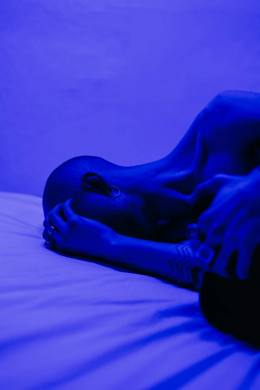 a person laying on a bed under a blue light, trending on pexels, massurrealism, purple - tinted, portrait of mournful, disrobed, blue and black