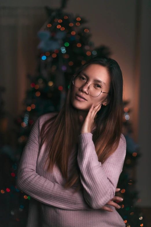 a woman standing in front of a christmas tree, pexels contest winner, hyperrealism, rounded eyeglasses, beautiful young asian woman, portrait soft low light, anna nikonova aka newmilky