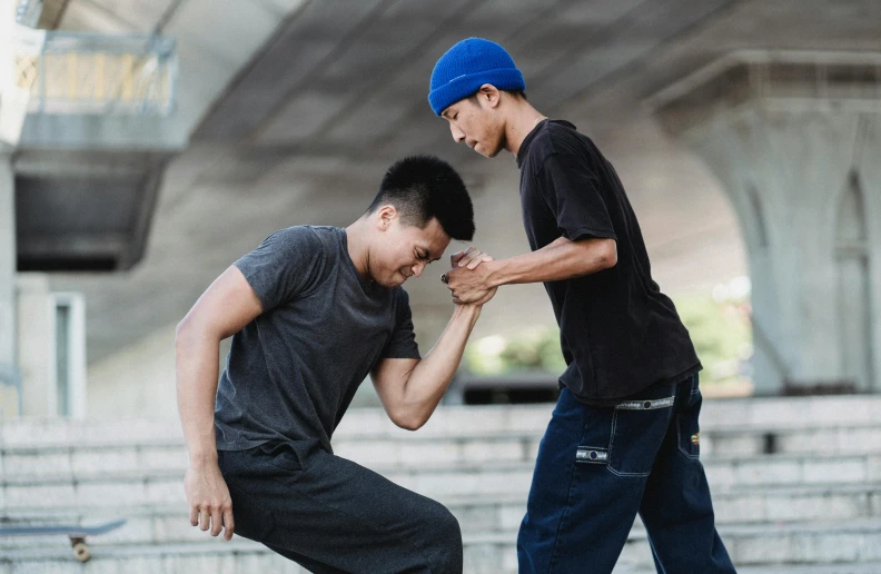 a couple of men standing next to each other on a skateboard, pexels contest winner, getting ready to fight, asian male, hands shielding face, bowater charlie and brom gerald