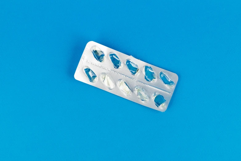 a pill pack sitting on top of a blue surface, crystal cubism, pierced, contracept, ffffound, adult