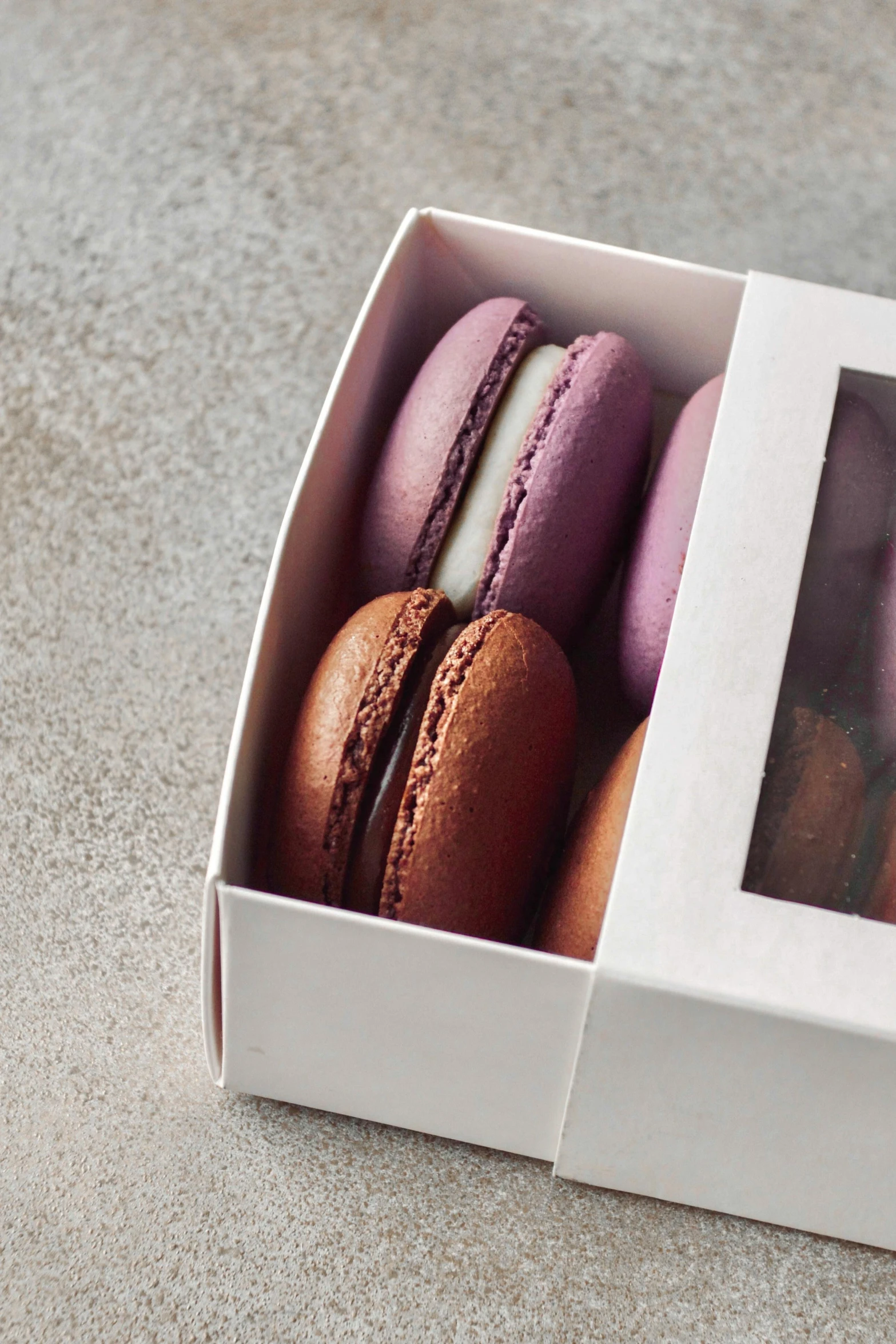 a close up of a box of macarons on a table, four, product image, purple, mix