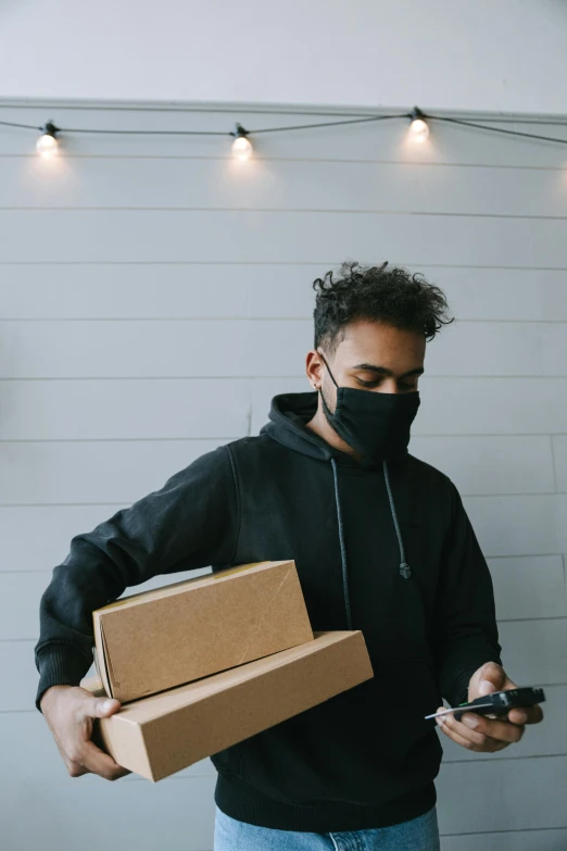 a man wearing a face mask while looking at his cell phone, by Adam Rex, pexels contest winner, delivering packages for amazon, black and brown colors, gif, light skin