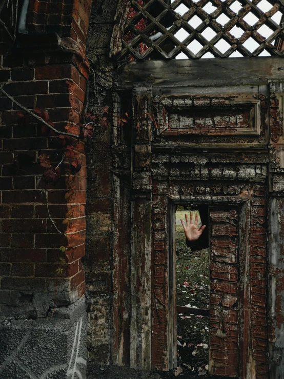 a close up of a doorway in a brick building, an album cover, by Lucia Peka, pexels contest winner, zombie reaching out of a grave, secret garden, hand, style of john atkinson grimshaw