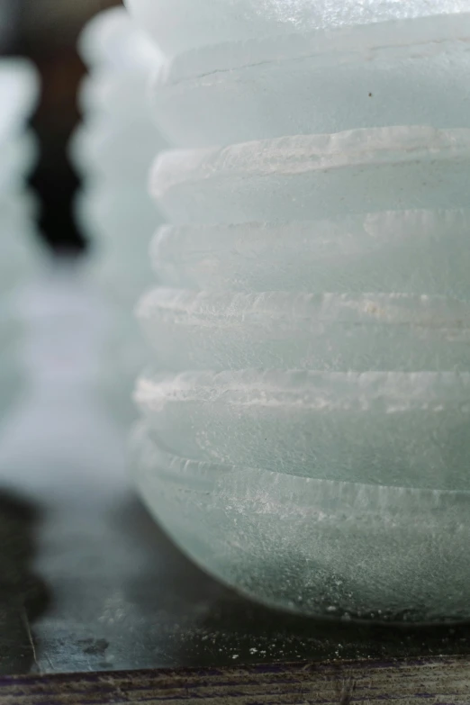 a pile of ice sitting on top of a wooden table, an abstract sculpture, unsplash, lanterns, spiral, close - up profile, porcelain