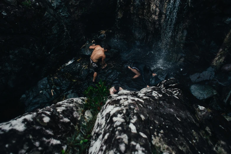a man standing on top of a rock next to a waterfall, by Elsa Bleda, pexels contest winner, happening, people swimming, hanging upside down from a tree, high angle view, jungle grunge