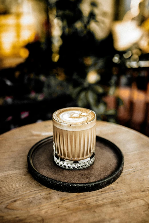 a cup of coffee sitting on top of a wooden table, cocktail in an engraved glass, aussie baristas, winter, magnolia