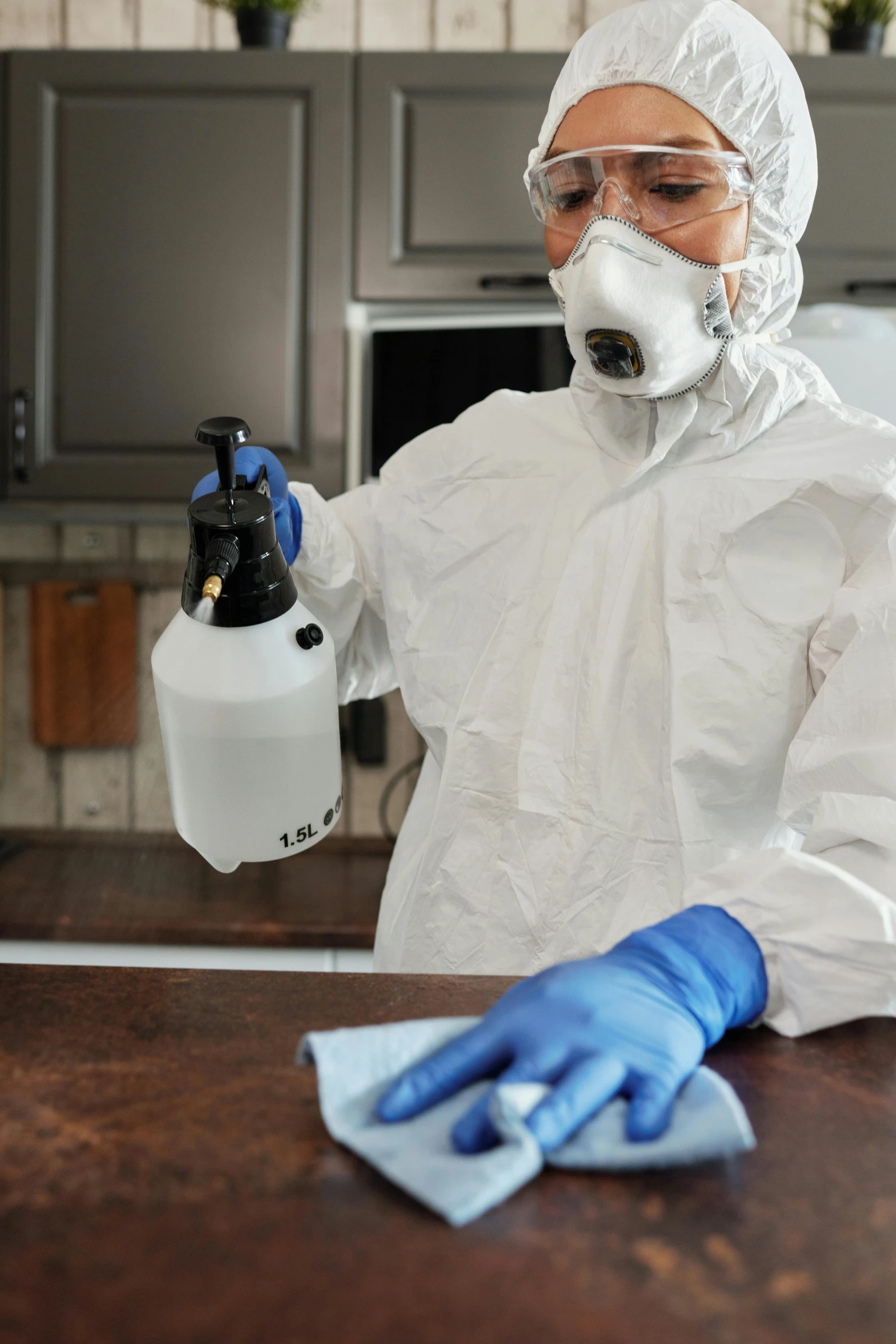 a person in protective gear cleaning a counter, a portrait, by Robert Medley, pexels, on kitchen table, spraying liquid, thumbnail, profile pic