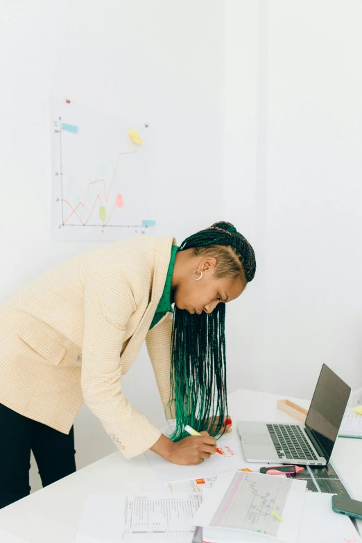 a woman leaning over a table with a laptop, a cartoon, trending on unsplash, standing in class, long afro hair, with a ponytail, serious business