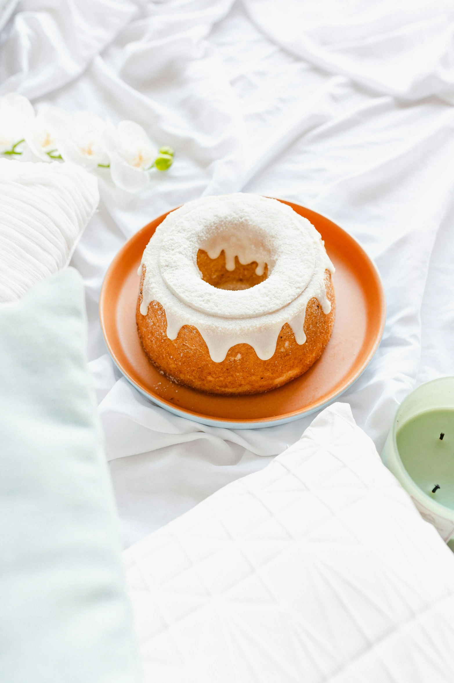 a close up of a plate of food on a bed, a still life, trending on unsplash, blender donut, white and orange, cake, pastel green
