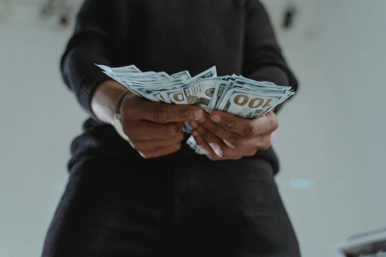 a person holding a bunch of money in their hands, by Matija Jama, pexels contest winner, sitting down, avatar image, black man, thicc