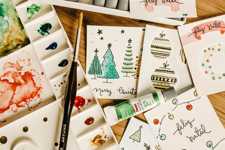 a bunch of cards sitting on top of a wooden table, a watercolor painting, trending on pexels, decorated ornaments, pen painting, holiday, cutest