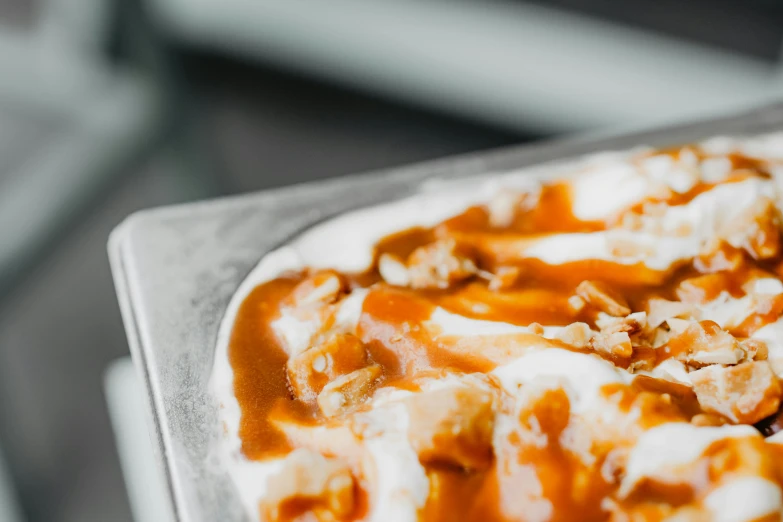 a pizza sitting on top of a pan covered in sauce, by Daniel Lieske, trending on pexels, ice cream, caramel, close-up product photo, paisley