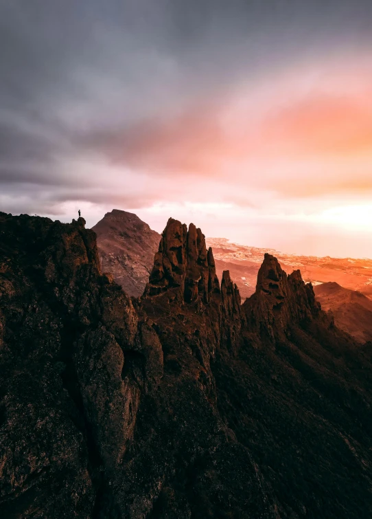 a person standing on top of a mountain at sunset, a matte painting, by Sebastian Spreng, pexels contest winner, tall stone spires, reunion island landscape, ultrawide lens”, wide high angle view