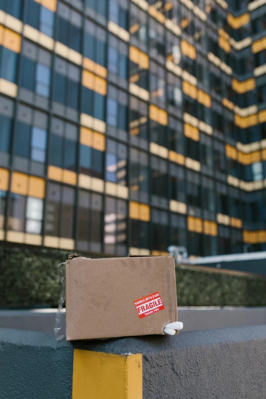 a box sitting on top of a curb next to a tall building, fragile, ecommerce photograph, traveller, sustainable materials