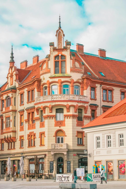 a large building sitting on the side of a road, inspired by Joseph von Führich, pexels contest winner, art nouveau, orange roof, in legnica, payne's grey and venetian red, ivory and copper