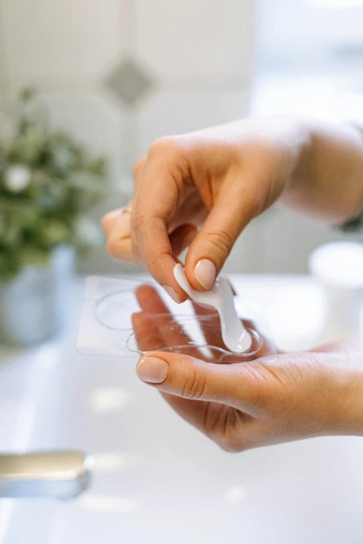 a close up of a person holding something in their hand, plasticien, nasal strip, hands on counter, plating, transparent