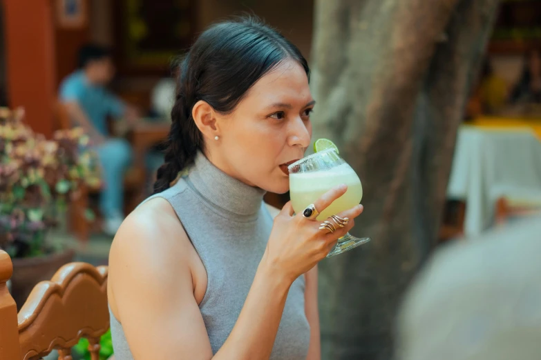a woman sitting at a table with a drink in her hand, inspired by Ruth Jên, pexels contest winner, lara croft eating durian, vanilla smoothie explosion, aussie baristas, profile image