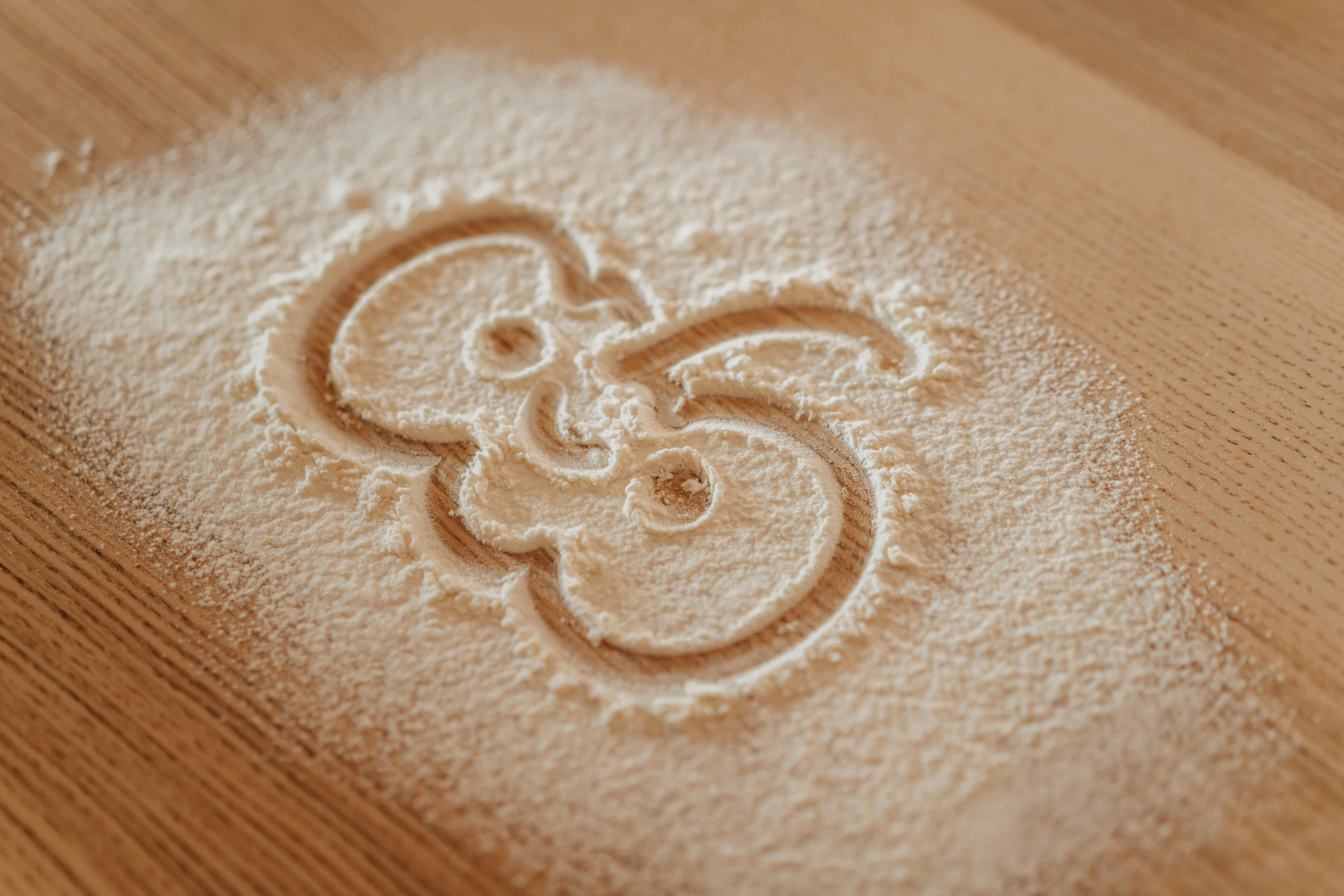 a wooden table topped with white powder on top of a wooden table, a stipple, by Adam Marczyński, trending on pexels, barn owl symbol in chest, covered in white flour, letter s, yinyang shaped